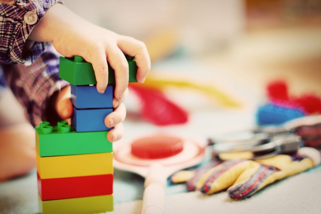 child's hands stacking colourful blocks