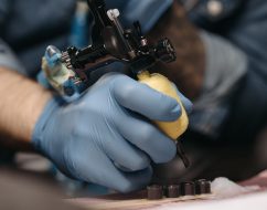 Tattoo artist with gloves operates a tattoo machine in a tattoo parlor setting